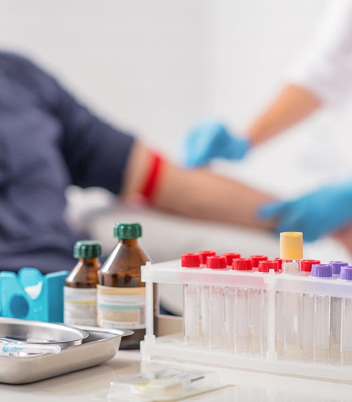 A person is sitting in front of some blood samples.